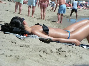 Brunette looking sexy on the beach in a blue thong bikini