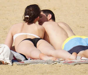 Sexy girl on the beach laying out and bending over in her bikini