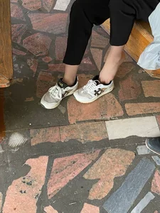 College Teen in Pants And Pantyhose Putting On Her Sneakers