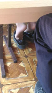 College teen girl's feet in pantyhose closeup under desk in classroom