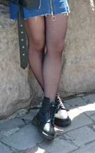 Cute Girl in Black Pantyhose with Crossed Legs on the River Embankment