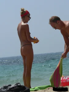 Topless skinny blonde lady in a g-string bikini at the beach