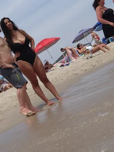Thick brunette with huge boobs on the beach in black swimsuit