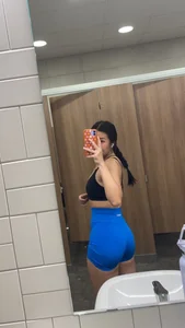 Sexy girl in spandex shorts taking a selfie in the toilet mirror