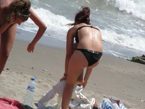 Sexy girl in black bikini dressing on the beach