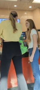 Two candid teens in tight pants and jeans at the counter