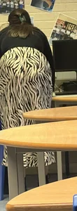 Teacher wearing a long zebra-patterned skirt bending over in class