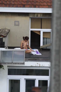 Neighbor on rooftop tanning in bikinis