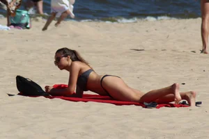 Hottie undressing from her red shorts to her bikini to layout on the beach