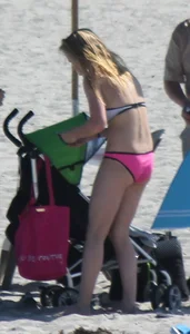 Skinny blonde girl on the beach in her pink and white bikini