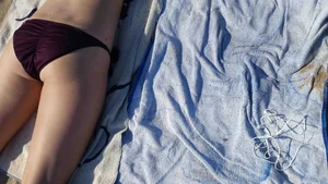 Hot girl laying on the beach in her purple bikini