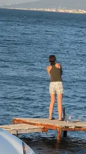 Girl in shorts fishing on a pier, nice slim legs