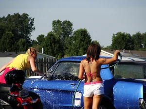 Group of cute girls at a car wash in bikinis and shorts