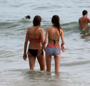 Skinny small boobed girl in a bikini on the beach with her friend