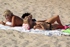 Topless mom and daughter on the beach getting some sun