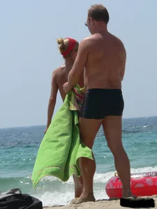 Topless skinny blonde lady in a g-string bikini at the beach