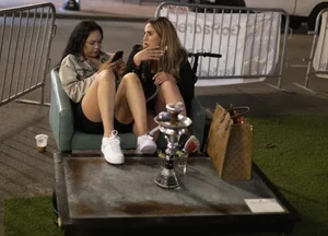 Two candid sexy female friends with nice slim bare legs sitting on a sofa in a street cafe creepshot