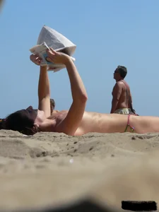 Topless beach milf looking sexy in a tiny g-string bikini