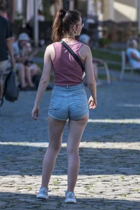 Sexy brunette chick with glasses in denim overalls showing her cheeks