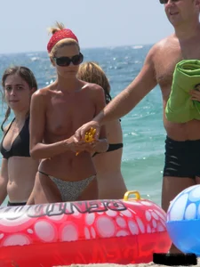 Topless skinny blonde lady in a g-string bikini at the beach