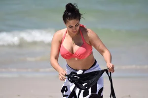 Huge boobed thick brunette babe on the beach in a bikini