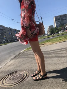 Hot street candid girl wearing a short dress and sandals standing on the crosswalk, wind is playing with her hair
