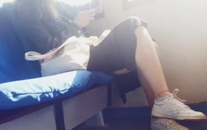 Girl in a Long Dress And Sneakers Sitting With Crossed Legs in a Public Train Creepshot