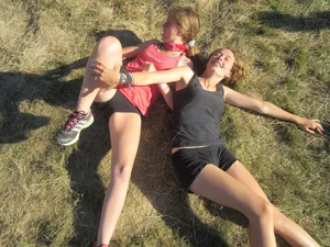 Couple of cute teens in shorts rolling on the grass laughing