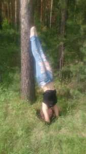 Girl in Torn Jeans Doing a Headstand in the Woods with her Tummy Visible