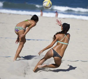 Hot girls playing beach volleyball in bikinis and shorts