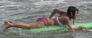 Brunette bikini girl on the beach and surfing in her bikini