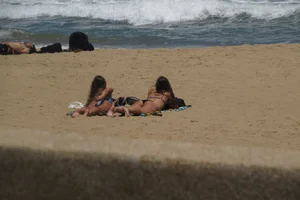 Two babes laying on the beach in bikinis with nice asses