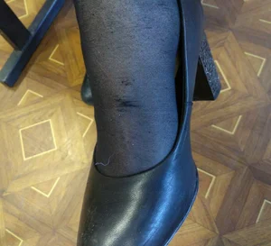 College Teen's Foot in Black Pantyhose And a High-Heeled Shoe Closeup Photo
