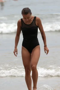 Skinny sexy lady on the beach in a black swimsuit