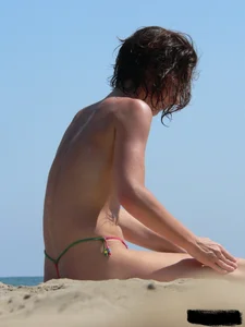 Topless beach milf looking sexy in a tiny g-string bikini