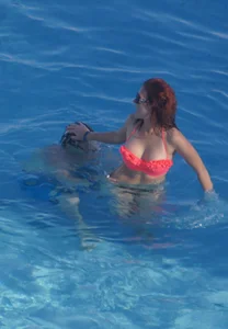 Sexy red haired girl in pink and black bikini at the pool