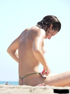 Topless beach milf looking sexy in a tiny g-string bikini