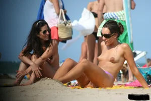2 topless girls at the beach in thongs