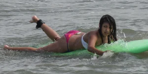 Brunette bikini girl on the beach and surfing in her bikini