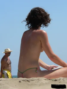 Topless beach milf looking sexy in a tiny g-string bikini