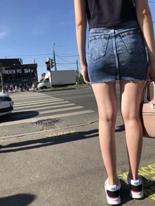 Cute Girl in a Short Denim Skirt Walking on a Street And Waiting on a Crosswalk Gallery