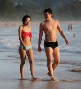Cute Asian in bikini on the beach with her boyfriend