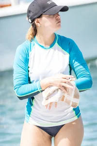 Girl in the water in a navy blue bikini bottom, shirt and hat with a nice ass