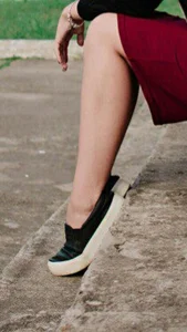 Girl in a Skirt Sitting on the Street Stairs With Her Feet on Tiptoes
