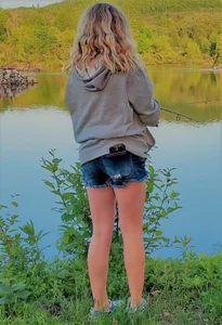 Blonde teen girl wearing denim shorts standing by the lake