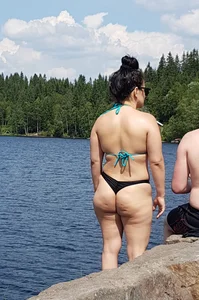 Thick brunette at the lake in a black thong bikini