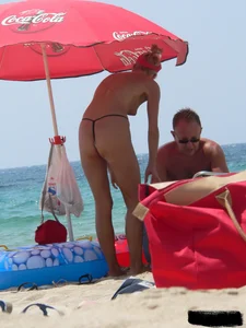 Topless skinny blonde lady in a g-string bikini at the beach