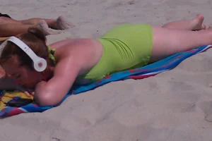 Redhead laying on the beach in green swimsuit
