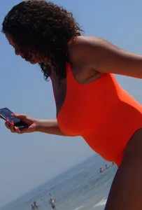 Beach girl with big boobs in an orange swimsuit