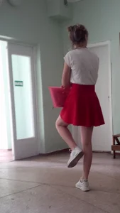 Young Candid Girl in a Red Skirt And Sneakers Standing on One Leg Creepshot